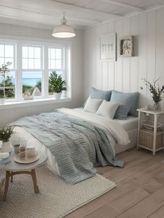 a bedroom with white walls and wood flooring has a large window overlooking the ocean