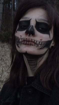 a woman with makeup painted to look like a skeleton in the woods, wearing black and white make up