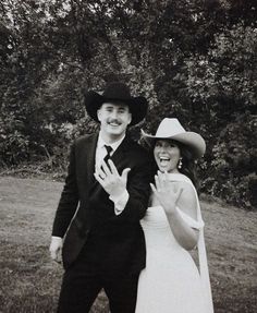 a man and woman dressed up in wedding attire posing for a photo together with trees in the background