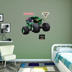 a bedroom with a bed, chair and monster truck wall decal