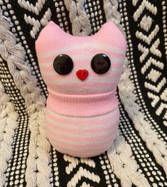 a pink cat stuffed animal sitting on top of a black and white blanket