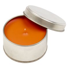 an orange candle in a metal tin on a white background, with the lid open