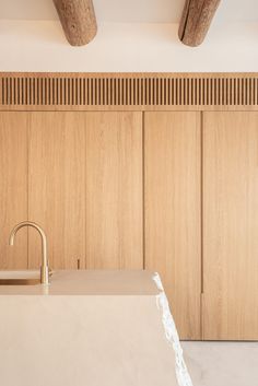 a kitchen counter with a sink and wooden cupboards on the wall behind it,