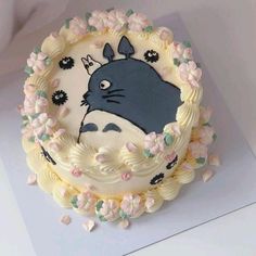 a cake decorated with an image of a totoro in the center and flowers around it