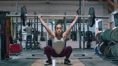 a woman squats on one leg while holding a barbell in front of her