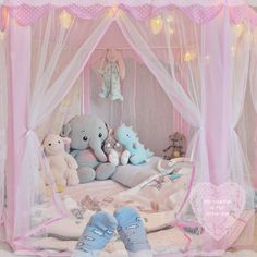 there is a pink canopy bed with stuffed animals in it and two blue shoes on the floor