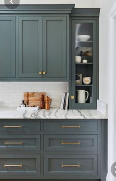 a kitchen with green cabinets and marble counter tops