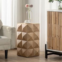 a vase with flowers in it sitting on a table next to a chair and sideboard