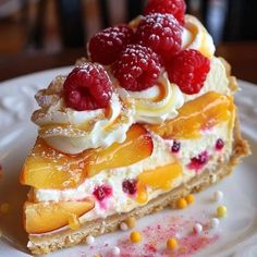 a piece of pie with raspberries and whipped cream on top sits on a white plate