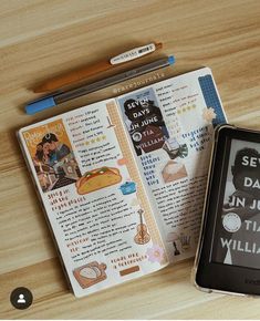 an open book sitting on top of a wooden table next to a smart phone and pen