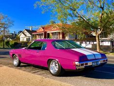 the pink car is parked on the side of the road