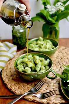 a person pouring dressing into two green bowls