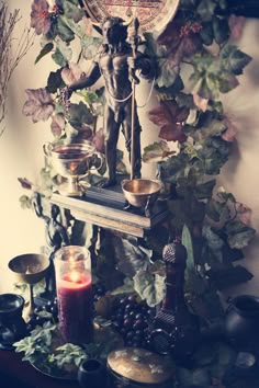 a table topped with candles next to a clock and figurine on top of a shelf