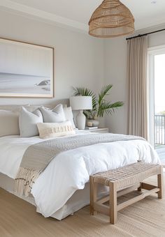 a bed with white sheets and pillows in a bedroom next to a large sliding glass door