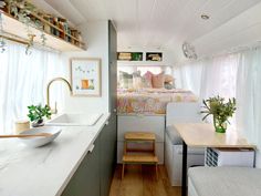 a small kitchen and living area in a tiny home with white walls, wood flooring and open shelving