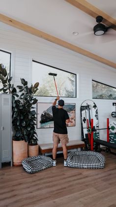 a man is playing golf in his living room with plants and other things on the wall