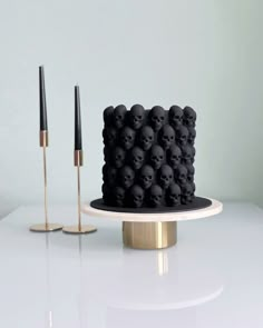 a black cake with skulls on it sitting on a table next to two gold poles