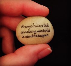 someone is holding a rock that says, always believe that something wonderful is about to happen