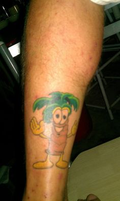 a man with a tattoo on his leg that has a cartoon character holding a palm tree