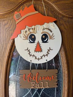 a welcome sign hanging from the front door of a house with a scarecrow face on it