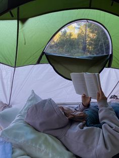 a person laying in a tent reading a book