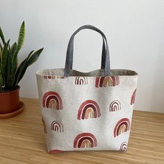 a white bag with rainbows on it sitting on top of a wooden table next to a potted plant