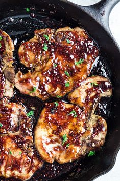 some meat is cooking in a skillet on the stove with sauce and parsley