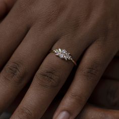 a woman's hand with a three stone ring on her left hand and the middle finger