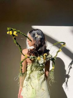 a woman with flowers in her hair standing against a wall