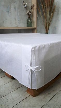 a white table cloth with a bow tied around it on a wooden stand in front of a wall