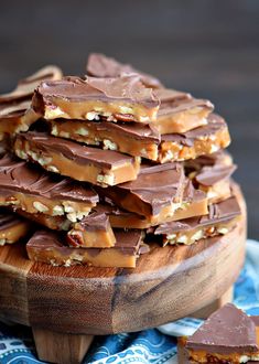 a wooden plate topped with pieces of chocolate covered pretzel barkle next to a blue and white napkin