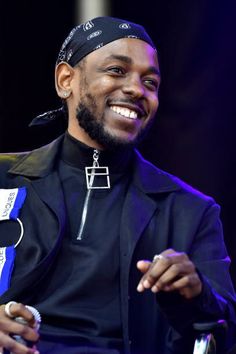 a man sitting in a chair smiling and wearing a bandana on top of his head