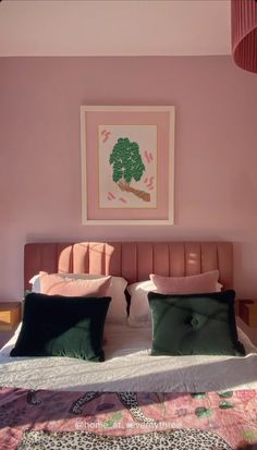 a bedroom with pink walls and green pillows