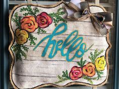 a door hanger with flowers and the word hello written in blue letters on it