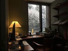 a desk with a lamp on it next to a window in a room filled with books