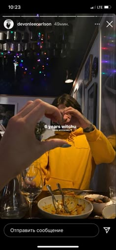 a woman in a yellow hoodie eating food from a bowl with her hands on the table