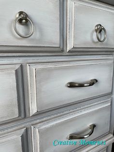 an old dresser has been painted white with silver handles and pulls on the drawer knobs