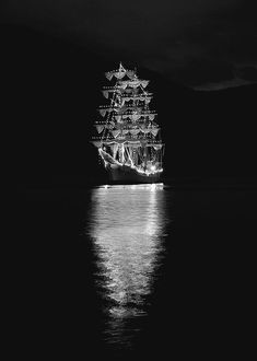 a large ship in the water at night with lights on it's masts