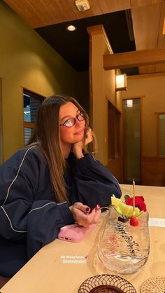 a woman sitting at a table with fruit on it