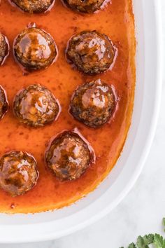 meatballs covered in tomato sauce on a white platter