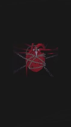 a red heart with chains attached to it on a black background in the middle of the night