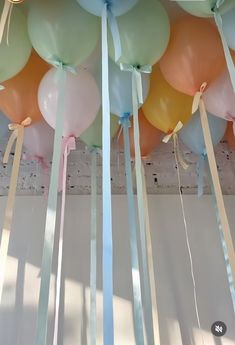 many balloons are hanging from the ceiling with ribbons