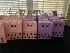 pink and purple bags with black polka dots are lined up in front of a window