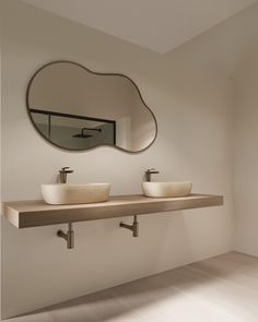 two white bowls are sitting on a shelf in front of a mirror that is above the sinks