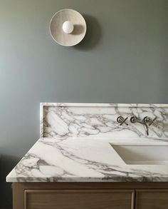 a bathroom vanity with marble counter top and white bowl on the wall next to it