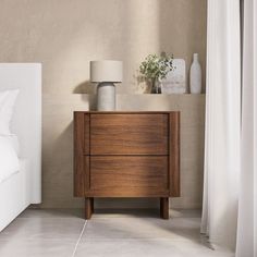 a bedroom with a bed, nightstand and lamp on the side table in front of it