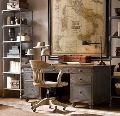 an old world map hangs in the corner of a room next to a desk and chair