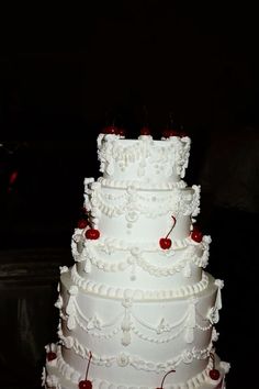 a large white wedding cake with cherries on it