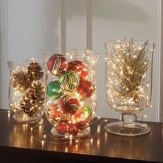 three glass vases filled with ornaments and lights