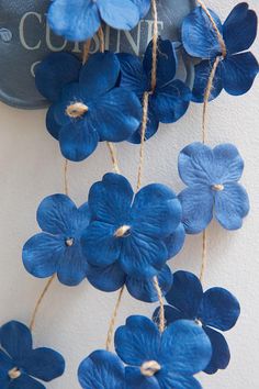 some blue flowers are hanging from a wall